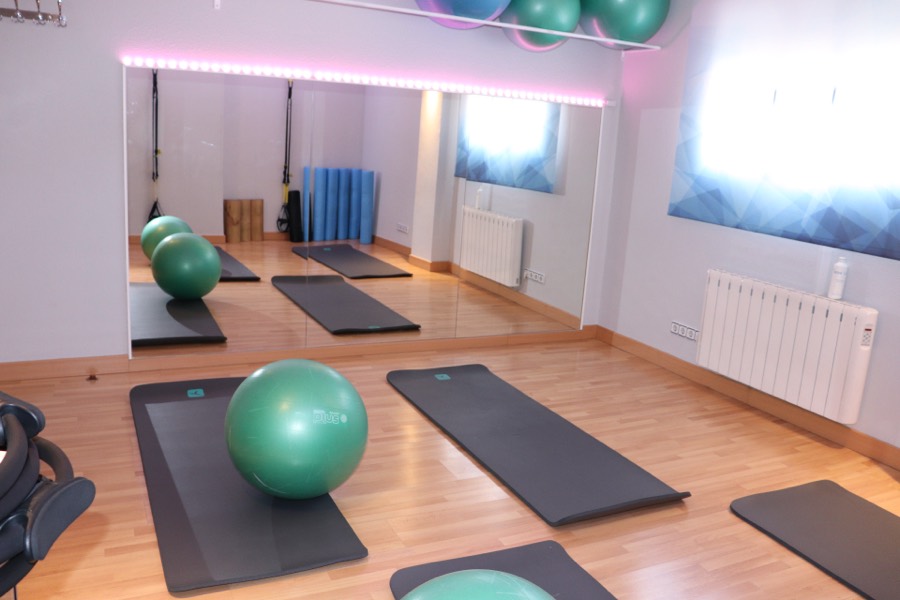 Sala de Pilates con colchonetas, fitballs y espejo